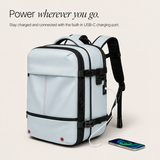 A light blue backpack with a built-in USB-C charging port, shown with a white charging cable connected to a smartphone on a light beige background. Text at the top reads 'Power wherever you go.