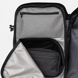 Close-up of an open backpack showing interior compartments, including a mesh zip pocket, a black main compartment, and a light  inner lining.