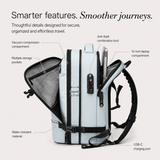 A light blue and backpack shown with callout labels explaining its features, including a vacuum compression compartment, multiple storage pockets, anti-theft combination lock, 16-inch laptop compartment, water-resistant material, expandable by 5 cm, and USB-C charging port, on a light beige background.