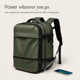 An olive green backpack with straps and trim, shown with a white charging cable plugged into its built-in USB-C port and a smartphone nearby. Text at the top reads 'Power wherever you go.