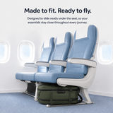  airplane seat with white armrests and a green carry-on bag underneath, shown in an airplane cabin with text reading 'Made to fit. Ready to fly.