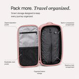 An open pink travel organizer bag shown on a light beige background with callout labels pointing to interior compartments and pockets, including a zipped separation pocket, breathable mesh pocket, built-in compression compartment, spacious main compartment, and organized interior storage.