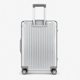 A silver aluminum hard-shell suitcase with vertical grooves, a telescoping handle extended, and four spinner wheels, shown against a plain light gray background.