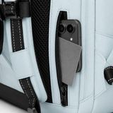 Close-up of a light blue backpack with mesh and straps, showing a side zipper pocket holding a dark smartphone and a gray card.